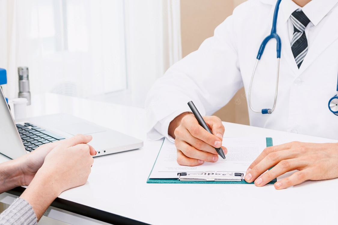 Two people discussing health insurance documents, one holding a pen and clipboard